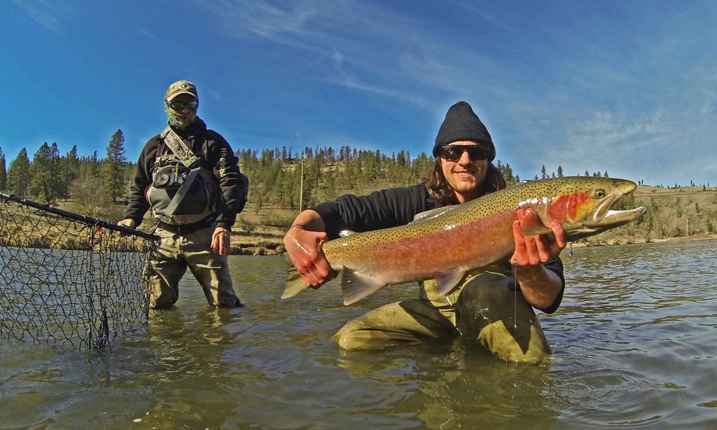 Guide and client with a large trout in shallow river water