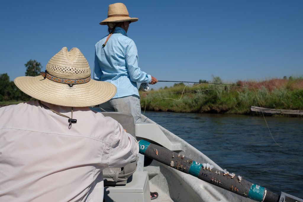 Anglers wearing sun hats in a drift boat on a Montana river