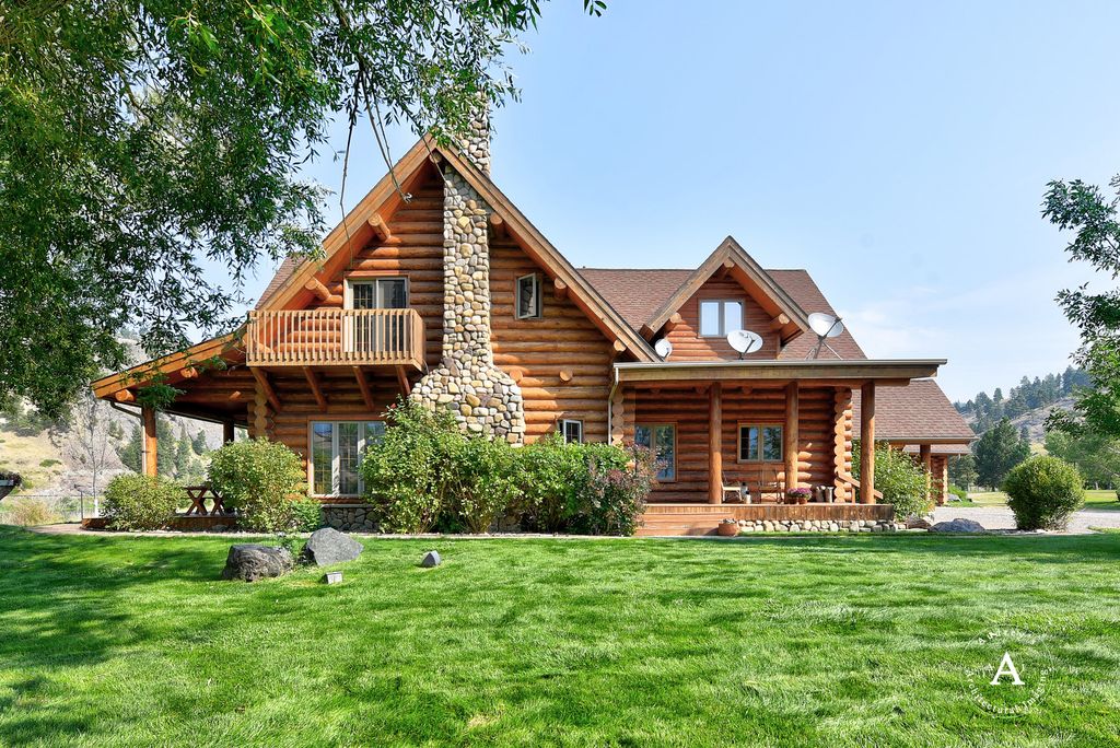 Log home surrounded by a green lawn and leafy trees