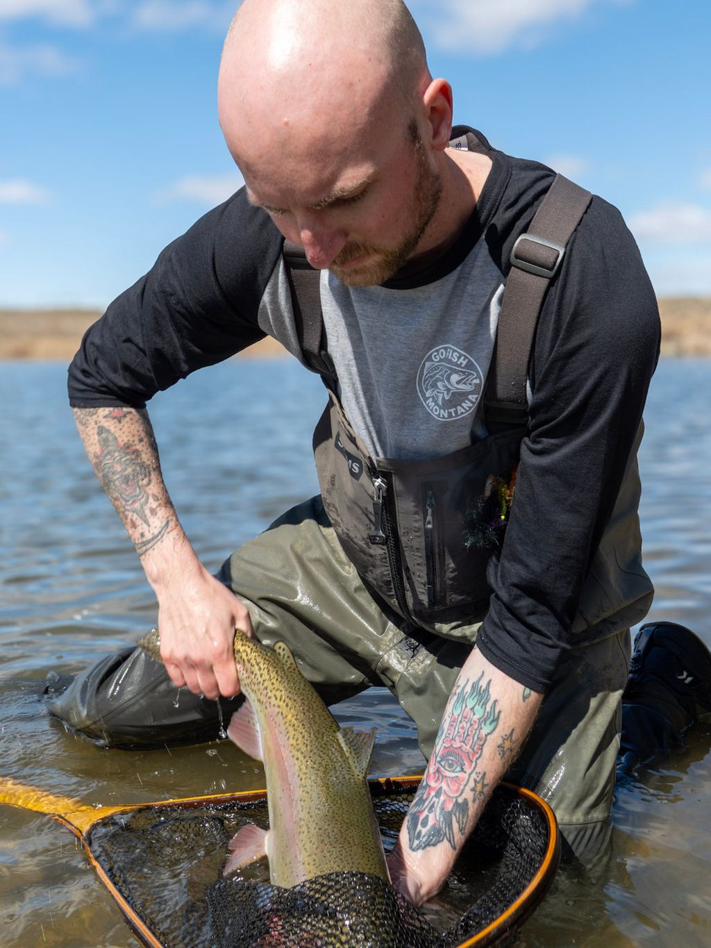 Angler wearing a GFM baseball tee while supporting a fish above a landing net
