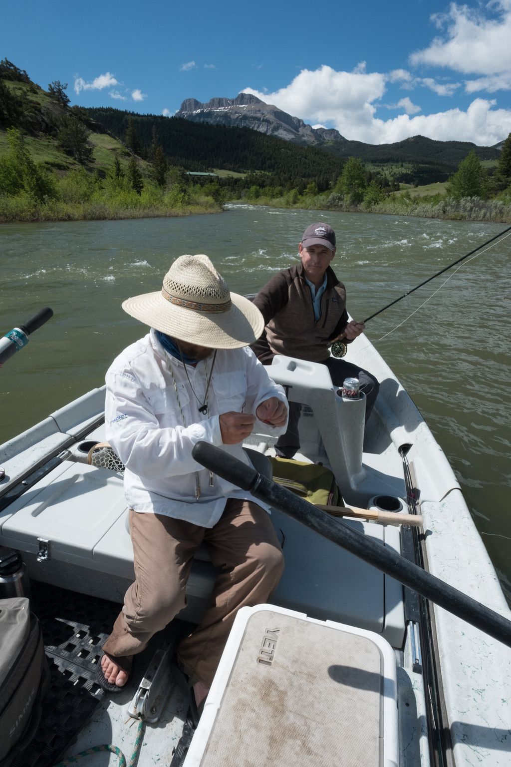 Anglers, tackle and a landing net in a drift boat on a river