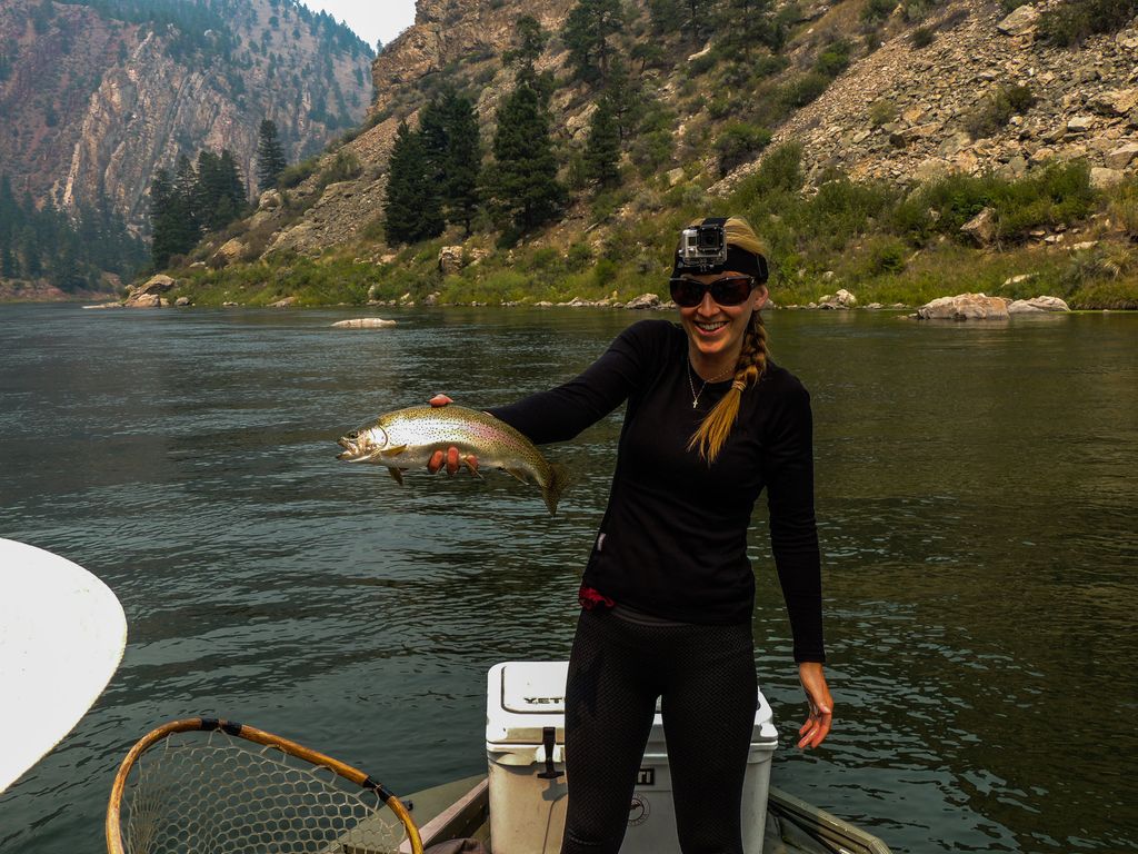 Angler holding a trout from a boat below the limestone cliffs at Gates of the Mountains