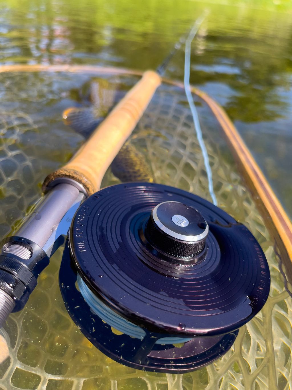 Traditional single-handed fly rod and reel resting in clear river water